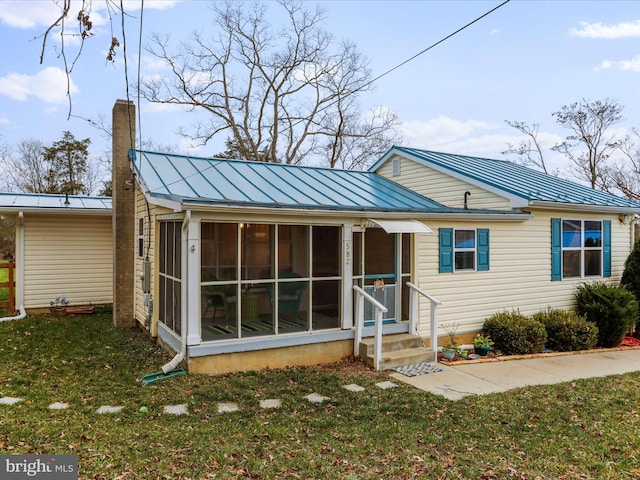 rear view of property with a sunroom and a lawn