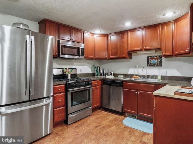 kitchen with sink, light hardwood / wood-style flooring, a textured ceiling, and appliances with stainless steel finishes