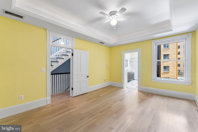 unfurnished room featuring ceiling fan, light wood-type flooring, crown molding, and a tray ceiling