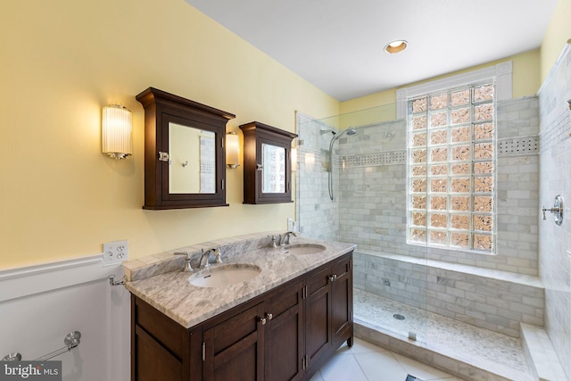 bathroom with tile patterned flooring, vanity, and a tile shower