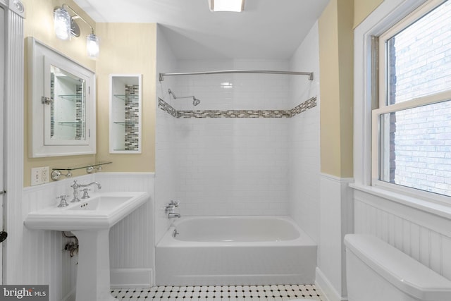 bathroom featuring toilet, tiled shower / bath combo, and tile patterned flooring