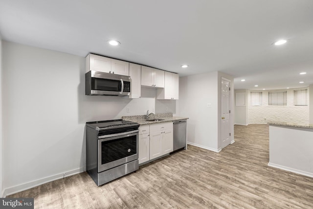 kitchen featuring white cabinets, appliances with stainless steel finishes, light hardwood / wood-style floors, and sink