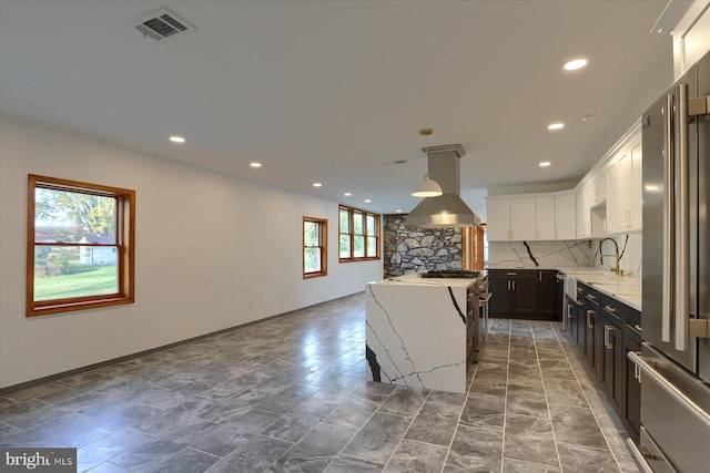 kitchen with dark brown cabinetry, a kitchen island, island exhaust hood, stainless steel fridge, and white cabinets