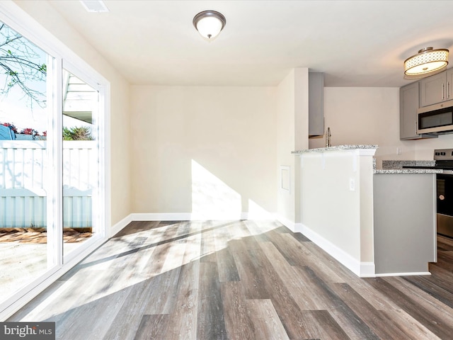 kitchen with dark wood-type flooring, gray cabinets, sink, and light stone counters