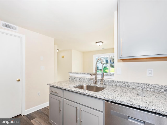 kitchen with dishwasher, sink, light stone counters, and dark hardwood / wood-style flooring