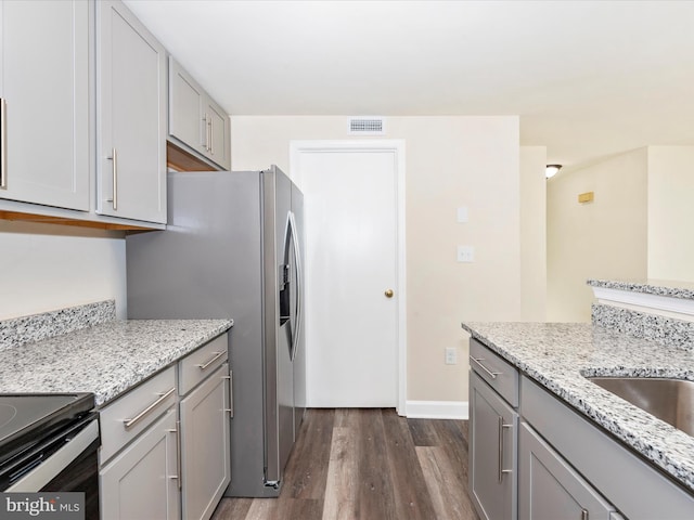 kitchen with dark wood-type flooring, gray cabinets, and light stone countertops