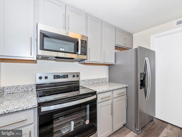 kitchen with light stone counters, dark hardwood / wood-style floors, and stainless steel appliances