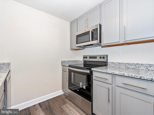 kitchen featuring dark hardwood / wood-style floors, light stone counters, and appliances with stainless steel finishes