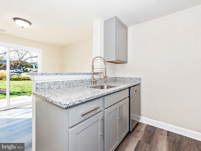 kitchen featuring dishwasher, sink, gray cabinetry, dark hardwood / wood-style floors, and light stone countertops