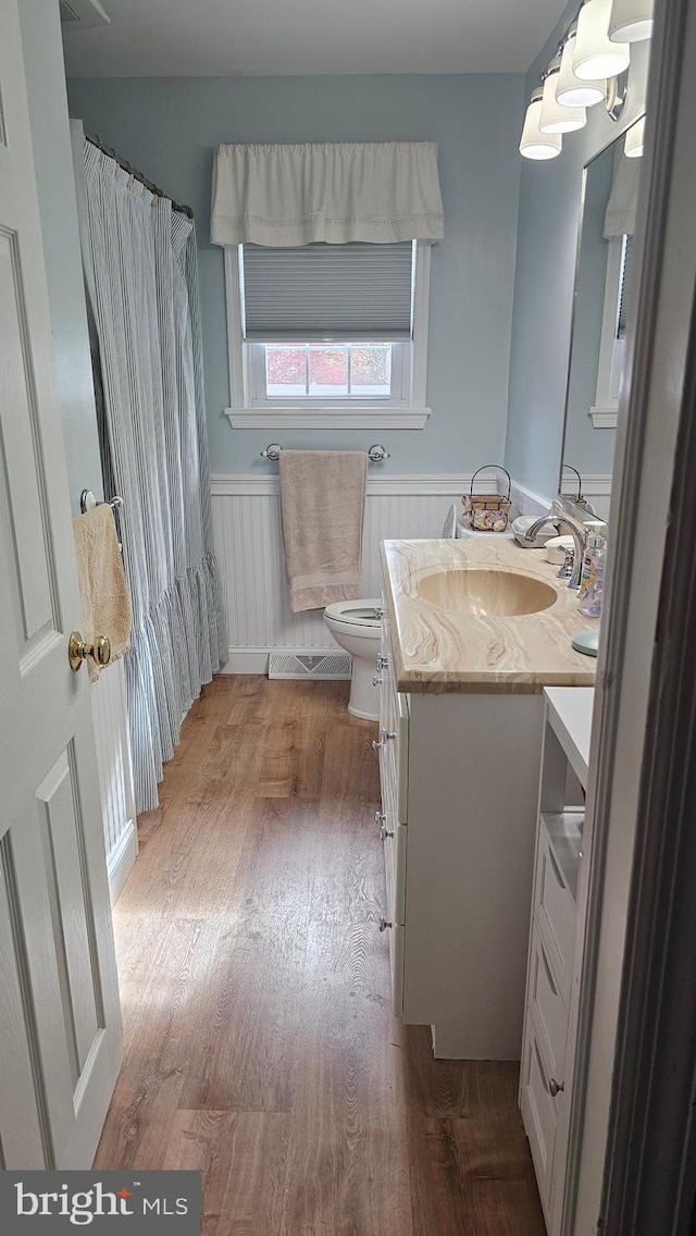 bathroom featuring hardwood / wood-style floors, vanity, toilet, and wooden walls