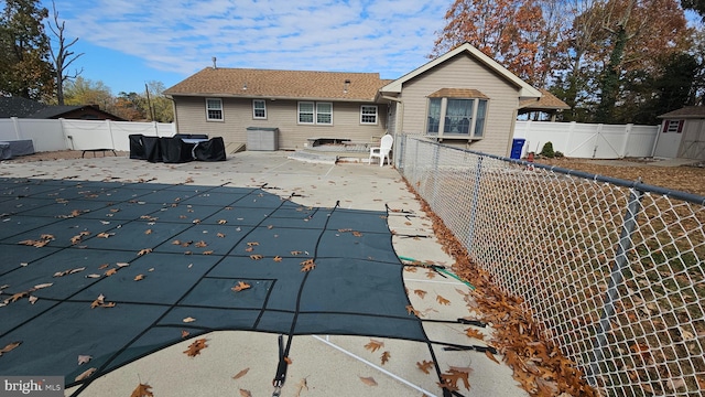 rear view of house featuring a patio and a covered pool