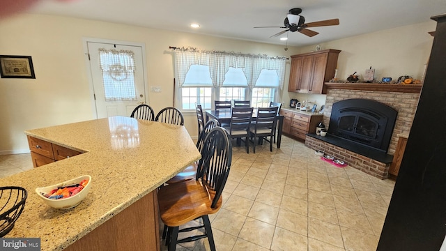 kitchen featuring a kitchen breakfast bar, light stone counters, ceiling fan, and light tile patterned floors