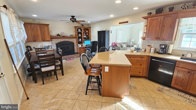 kitchen with a kitchen bar, backsplash, ceiling fan, black dishwasher, and a kitchen island