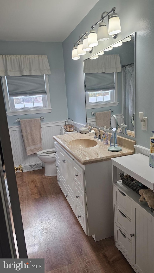 bathroom featuring a wealth of natural light, toilet, vanity, and hardwood / wood-style flooring