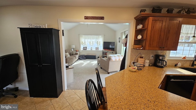 kitchen with light carpet, light stone countertops, backsplash, vaulted ceiling, and dishwasher