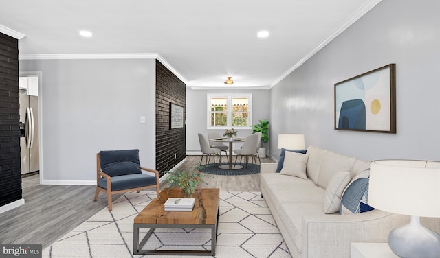 living room with light hardwood / wood-style floors, brick wall, a baseboard heating unit, and ornamental molding