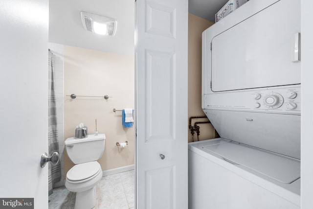 clothes washing area with light tile patterned flooring and stacked washer / dryer