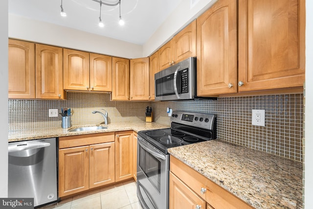 kitchen with light stone counters, light tile patterned flooring, stainless steel appliances, decorative backsplash, and sink