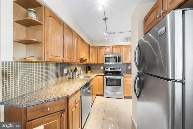 kitchen featuring light tile patterned flooring, sink, appliances with stainless steel finishes, light stone countertops, and decorative backsplash