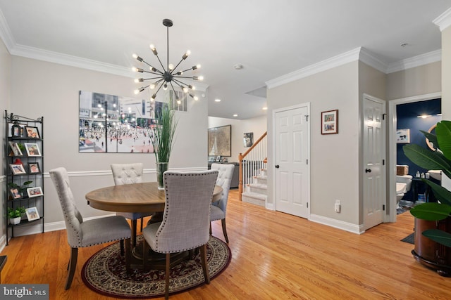 dining area featuring light wood-type flooring, an inviting chandelier, and crown molding