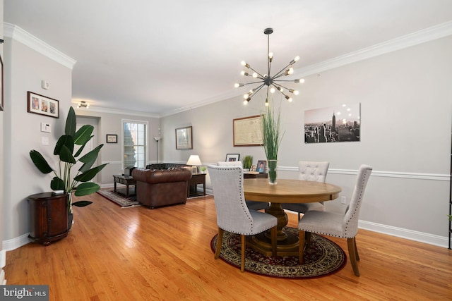 dining area with ornamental molding, an inviting chandelier, and light hardwood / wood-style floors