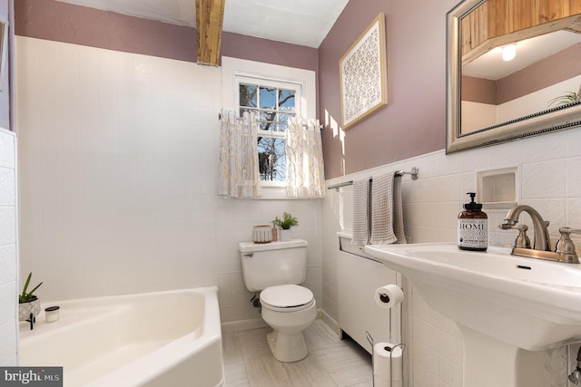 bathroom featuring tile walls, toilet, a sink, tile patterned floors, and a bathing tub