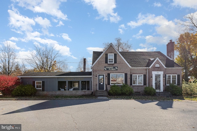 view of front of house with a chimney and brick siding