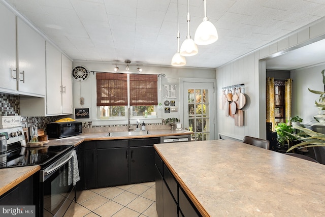 kitchen with stainless steel appliances, white cabinetry, sink, light tile patterned floors, and hanging light fixtures