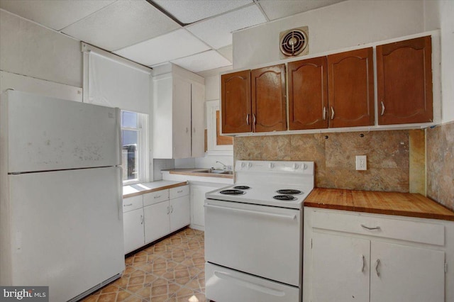 kitchen featuring white cabinets, decorative backsplash, a paneled ceiling, light tile patterned floors, and white appliances