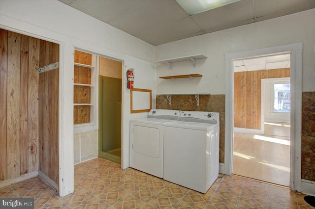 washroom with washing machine and dryer, wooden walls, and light tile patterned floors