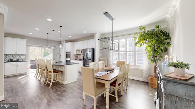 dining area featuring dark hardwood / wood-style floors, sink, an inviting chandelier, and crown molding