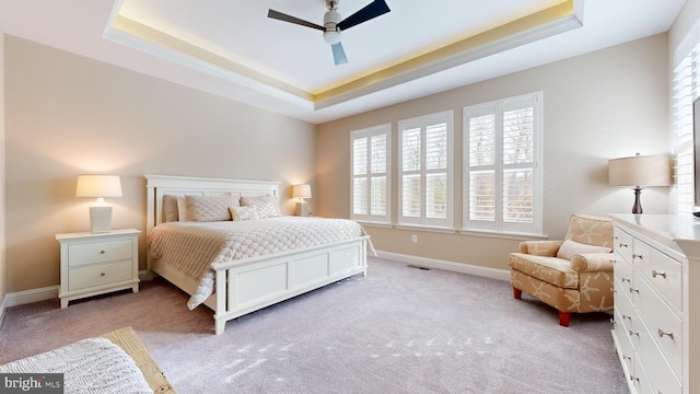 carpeted bedroom featuring ceiling fan and a tray ceiling