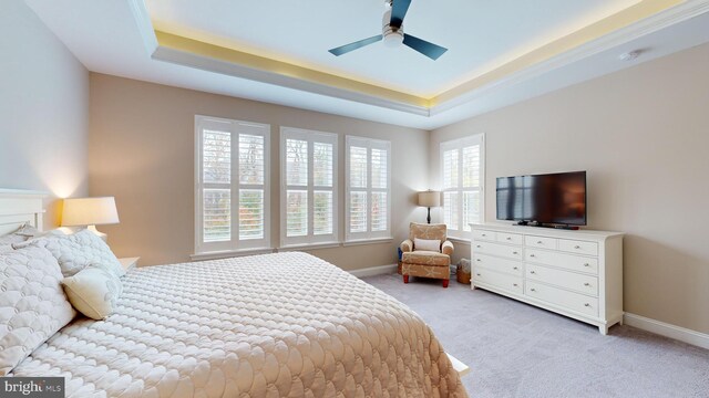 bedroom with light carpet, ceiling fan, and a raised ceiling