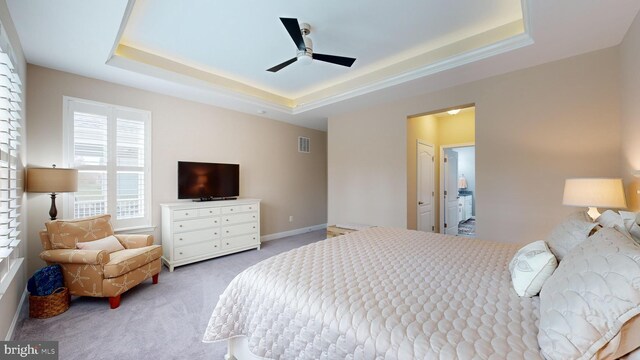 carpeted bedroom with ceiling fan and a raised ceiling