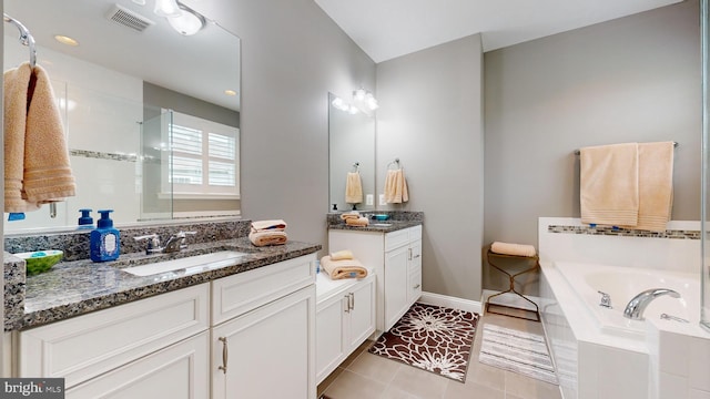 bathroom with vanity, tile patterned floors, and tiled tub