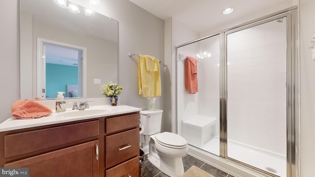 bathroom with vanity, a shower with shower door, tile patterned floors, and toilet