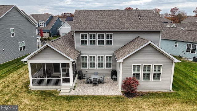 back of property with a lawn, a sunroom, and a patio area