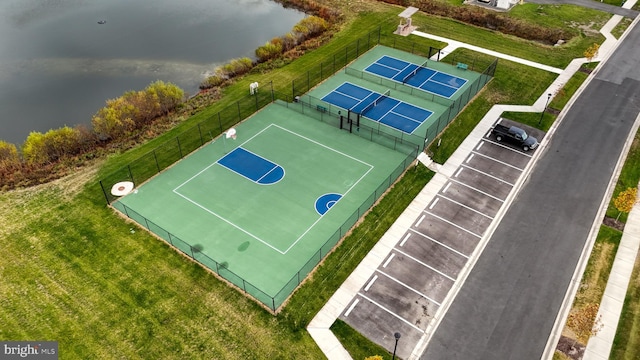 view of sport court with tennis court, a water view, and a yard