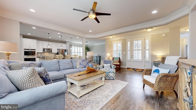 living room with dark wood-type flooring, ceiling fan, and ornamental molding