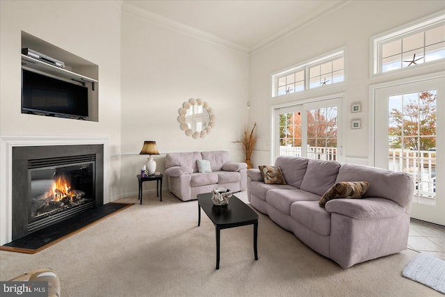 carpeted living room featuring a high ceiling, a healthy amount of sunlight, and crown molding