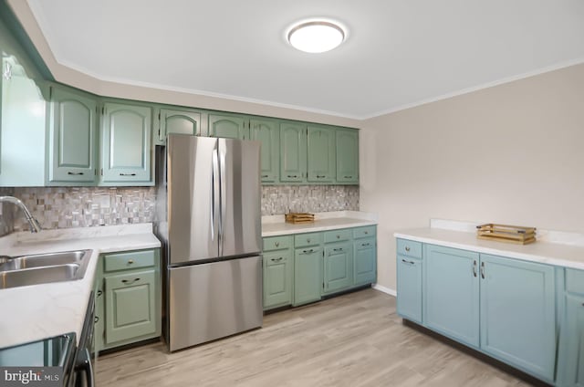 kitchen with crown molding, backsplash, stainless steel refrigerator, sink, and light hardwood / wood-style floors