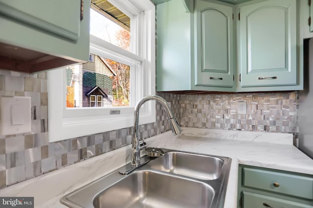 kitchen featuring backsplash, sink, light stone counters, and green cabinetry