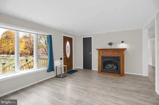 unfurnished living room with a wealth of natural light, crown molding, and light hardwood / wood-style flooring