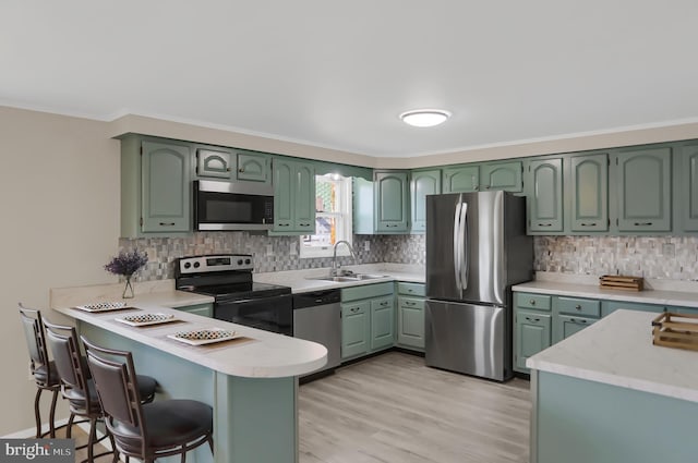 kitchen with stainless steel appliances, sink, kitchen peninsula, and green cabinetry