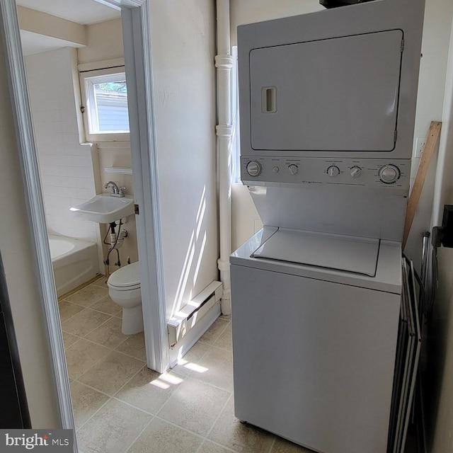 clothes washing area with sink, stacked washing maching and dryer, and light tile patterned flooring