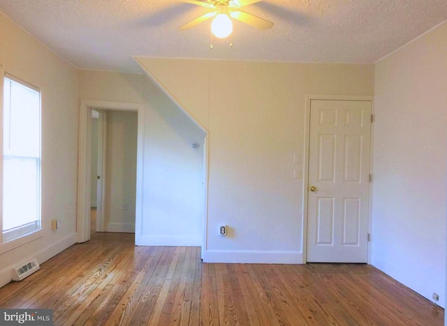 empty room featuring ceiling fan, light hardwood / wood-style flooring, and a textured ceiling