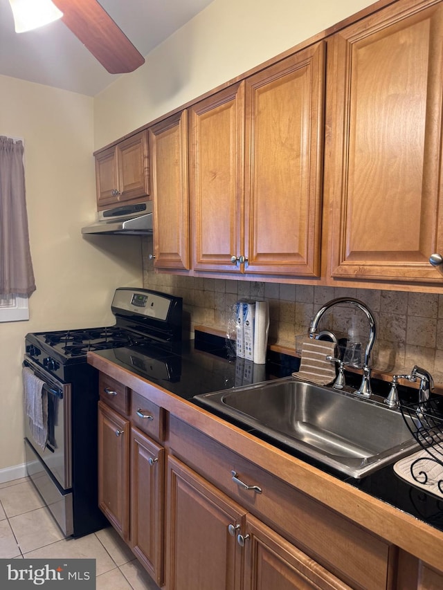 kitchen with light tile patterned flooring, sink, gas range, and tasteful backsplash