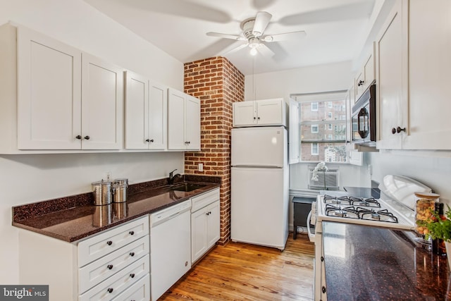 kitchen with sink, white cabinets, dark stone countertops, white appliances, and light hardwood / wood-style flooring