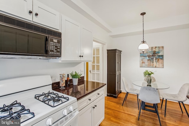 kitchen with light wood-type flooring, decorative light fixtures, white gas range, and white cabinets