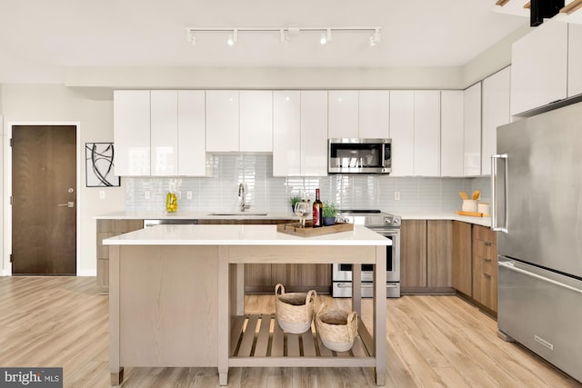 kitchen with light hardwood / wood-style flooring, white cabinets, sink, and stainless steel appliances